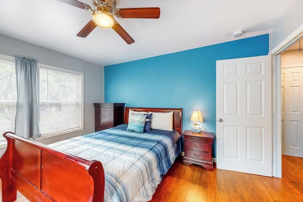 A bedroom with a wooden bed, a nightstand, a ceiling fan, and a door.