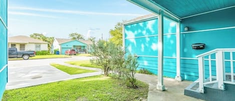 Ein Wohnhaus mit überdachter Veranda, kleinem Rasen und Auffahrt.
