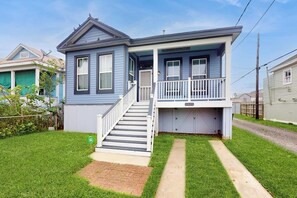 A two-story house with a front porch, a staircase leading to the entrance, and a well-maintained lawn. - Galveston Getaway - Historic Home Near the Beach (Galveston)