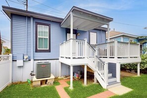 Ein zweistöckiges Haus mit einer Veranda und einer kleinen Terrasse.