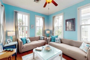 Ein Zimmer mit zwei Sofas, einem Glastisch und einem Deckenventilator.