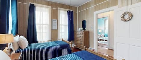 Ein Schlafzimmer mit zwei Betten, einem Schminktisch und einer Tür zu einem anderen Raum.