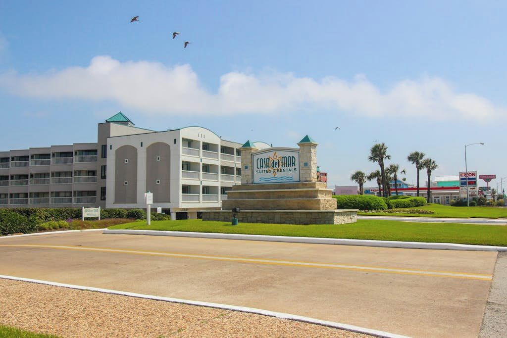 Um hotel com uma placa indicando 'Casa de Mar Suites & Rentals' e um posto de gasolina ao fundo.