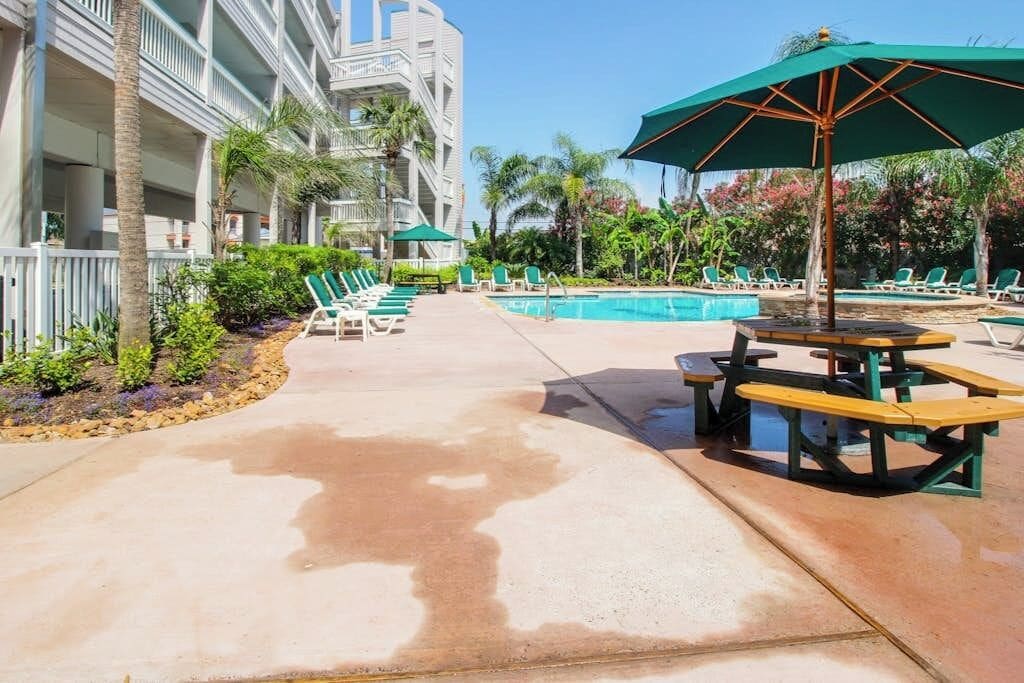 A pool area with lounge chairs and a picnic table.