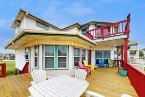A two-story house with a wooden deck, multiple windows, and outdoor seating. - Wait 'N Sea - 2-Minute Walk to the Beach (Galveston)