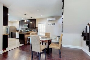 Une cuisine moderne avec des meubles de couleur sombre, un îlot central et un coin repas doté de chaises en osier.
