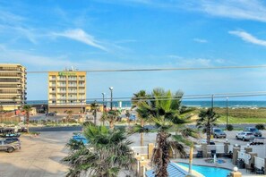A hotel with a pool area, palm trees, and a view of the ocean. - Leeward Isles 9303 - Pool, Walk to Beach, Dogs OK (Corpus Christi)