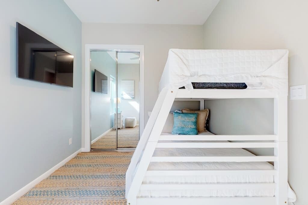 A bunk bed with a pillow and a flat-screen TV mounted on the wall.