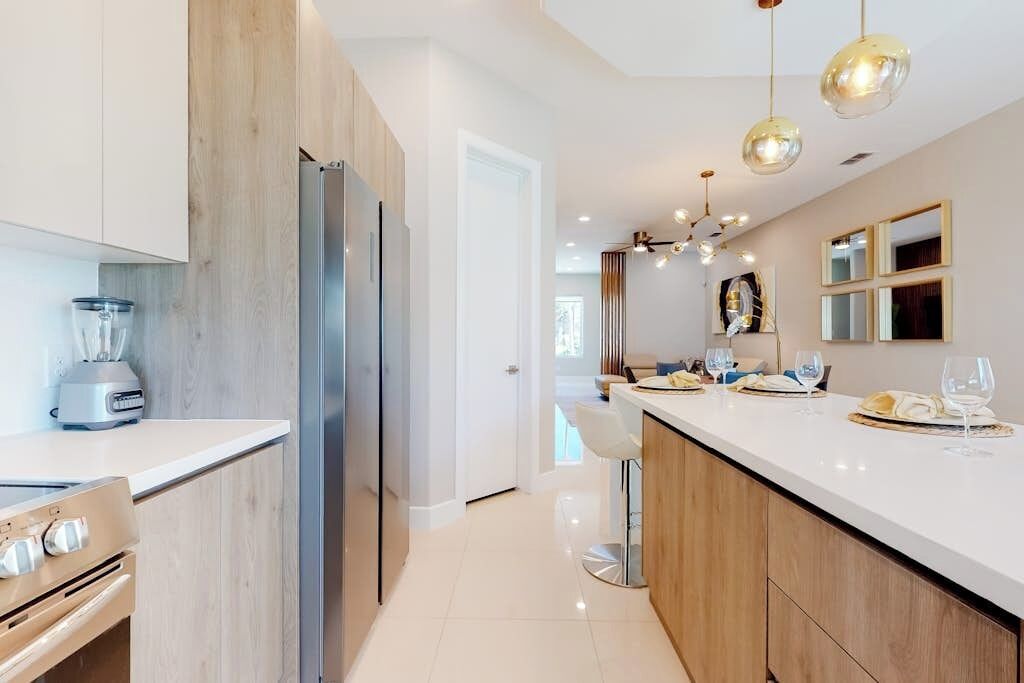 A modern kitchen with a central island, stainless steel appliances, and pendant lighting.