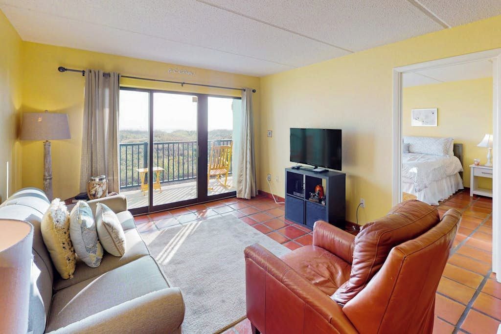Een kamer met een bank, een televisie, een balkon met uitzicht en een bed.