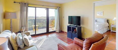 Une pièce comprenant un canapé, un téléviseur, un balcon avec vue et un lit.