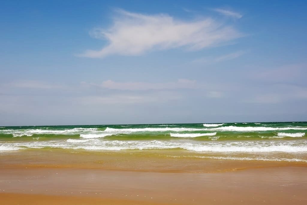 A beach with waves and a clear sky.