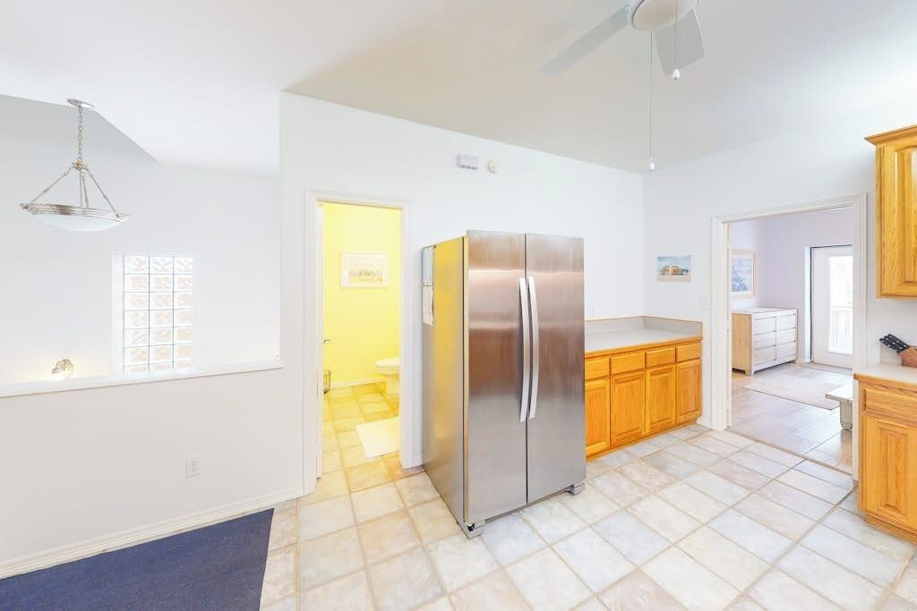 A modern kitchen with a stainless steel refrigerator, wooden cabinets, and a tiled floor.