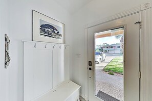 A white door with a glass panel, a bench, and a wall-mounted coat rack with hooks. - Acapulco Townhouse - Walk to Beach & Dog-Friendly (South Padre Island)