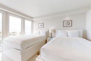 Habitación de hotel con dos camas, una mesita de noche, una lámpara y cuadros en la pared.