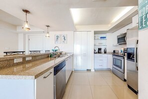 Una cocina moderna con armarios blancos, electrodomésticos de acero inoxidable e iluminación colgante.