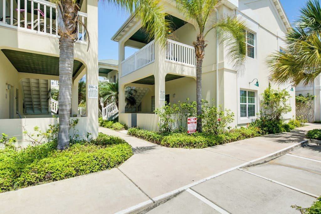 A multi-story residential building with balconies, a covered walkway, and a parking area.