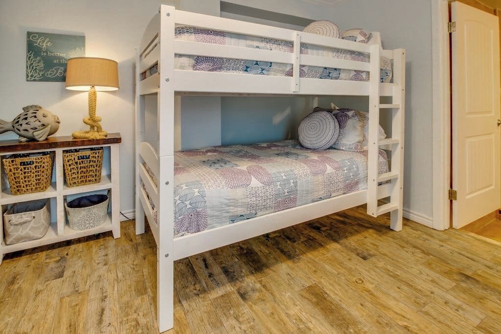 Ein Stockbett mit einem gemusterten Bettbezug, einer Lampe, Körben und einer Wanddekoration.