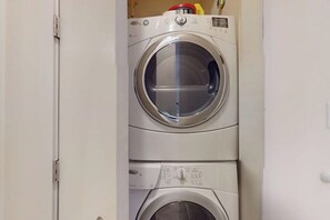 A stacked washer and dryer unit in a laundry room. - The Diamond Penthouse (Galveston)