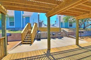 Eine überdachte Terrasse im Freien mit einer Holztreppe, die zu einem Grillplatz führt.