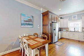 A kitchen with white cabinetry, a wooden dining table with chairs, and a painting on the wall. - Fun In The Sun - Boat Slip, Pool & Sundeck (Corpus Christi)