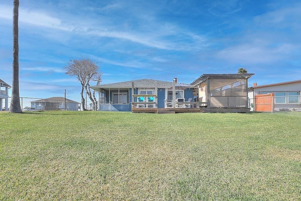 A residential property with a covered patio, a garage, and a lawn.