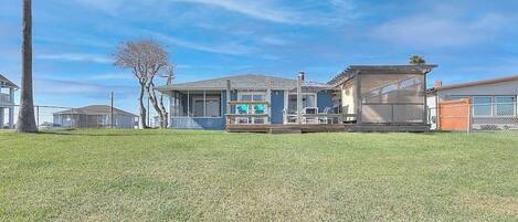 A residential property with a covered patio, a garage, and a lawn.
