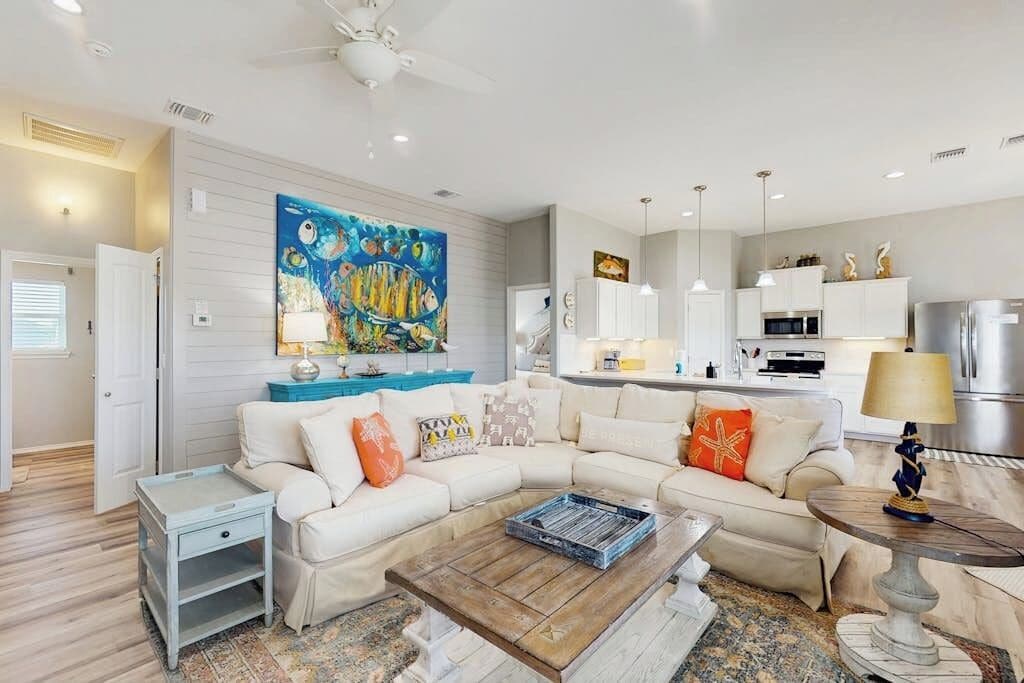 A modern living room with a sectional sofa, a coffee table, and a kitchen in the background.