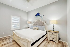 A bedroom with a bed, bedside lamps, a wall-mounted artwork, and a window with blinds. - Gulf Breeze - Pool, Boat Launch & Fishing (Rockport)