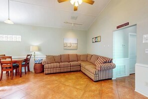 A living room with a sectional sofa, a dining table with chairs, a lamp, and a ceiling fan. - Marquesas 401 - Shared Pool, Patio & Dogs OK (Corpus Christi)