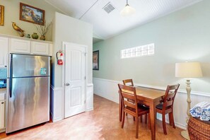 A kitchen with a stainless steel refrigerator, white cabinetry, a dining table with chairs, and a wall-mounted fire extinguisher. - Marquesas 401 - Shared Pool, Patio & Dogs OK (Corpus Christi)