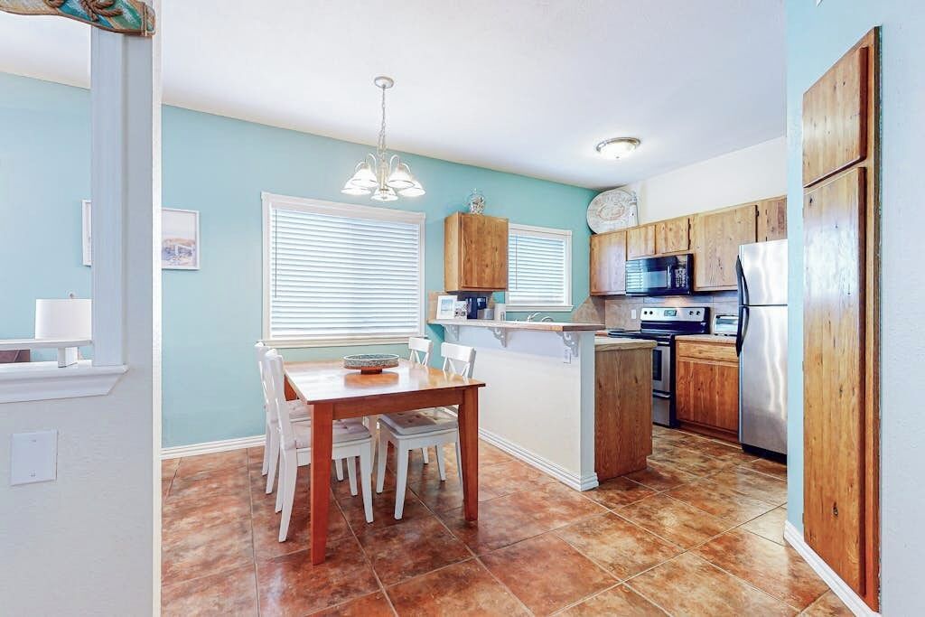 A kitchen with wooden cabinets, a dining table with chairs, and a built-in island.