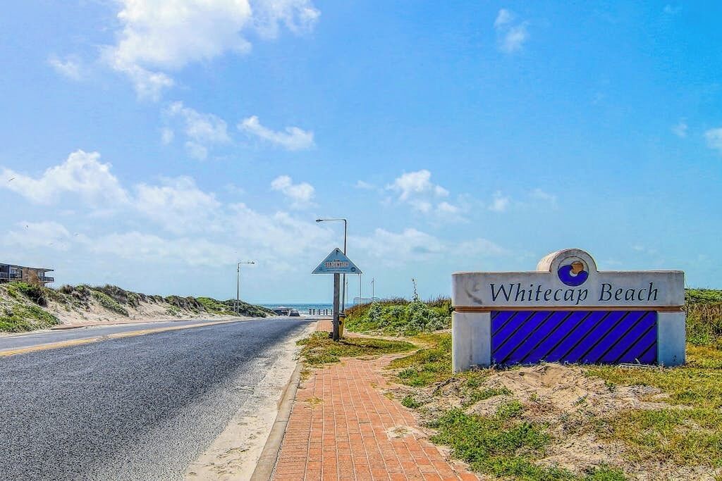 A road leading to a beach area with a sign reading 'Whitecap Beach.'