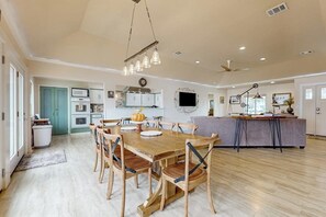 A spacious kitchen with a dining area, a large wooden table, and a modern ceiling fan. - Coral Cove - Waterfront with Amazing Views (Rockport)