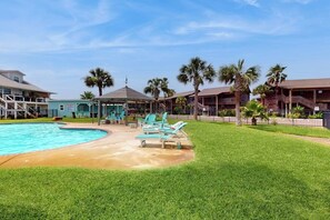 A hotel with a swimming pool, lounge chairs, and palm trees. - Tranquil Turtle #503 (Rockport)
