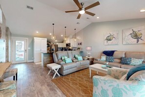 A spacious living area with a ceiling fan, a kitchen in the background, and a dining area. - Tranquil Turtle #503 (Rockport)
