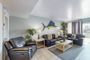 A modern living room with leather sofas, a coffee table, and a wall-mounted fish sculpture. - Puente Vista 133 - Bay-View Deck & Shared Pool (Corpus Christi)
