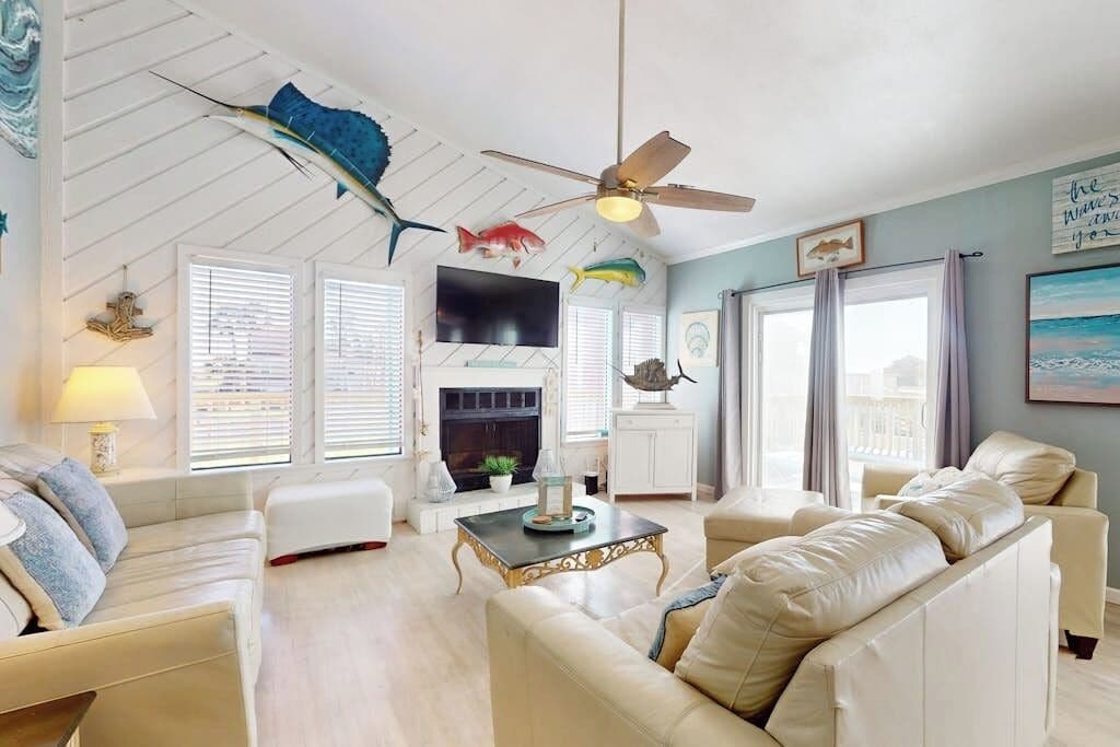 Un salon doté d’une cheminée, d’un ventilateur de plafond et décoré avec des éléments sur le thème des poissons.