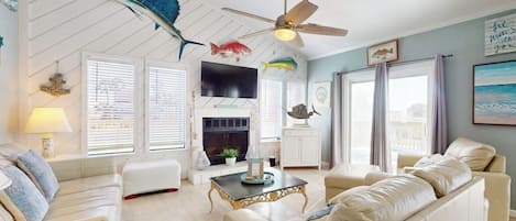 A living room with a fireplace, ceiling fan, and fish decorations.