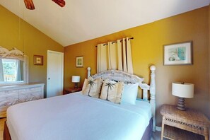 A bedroom with a large bed, a bedside table with a lamp, and a window with curtains. - Seas the Day Getaway (Port Aransas)
