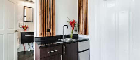A modern kitchen with dark wood cabinets, a stainless steel refrigerator, and a black countertop.