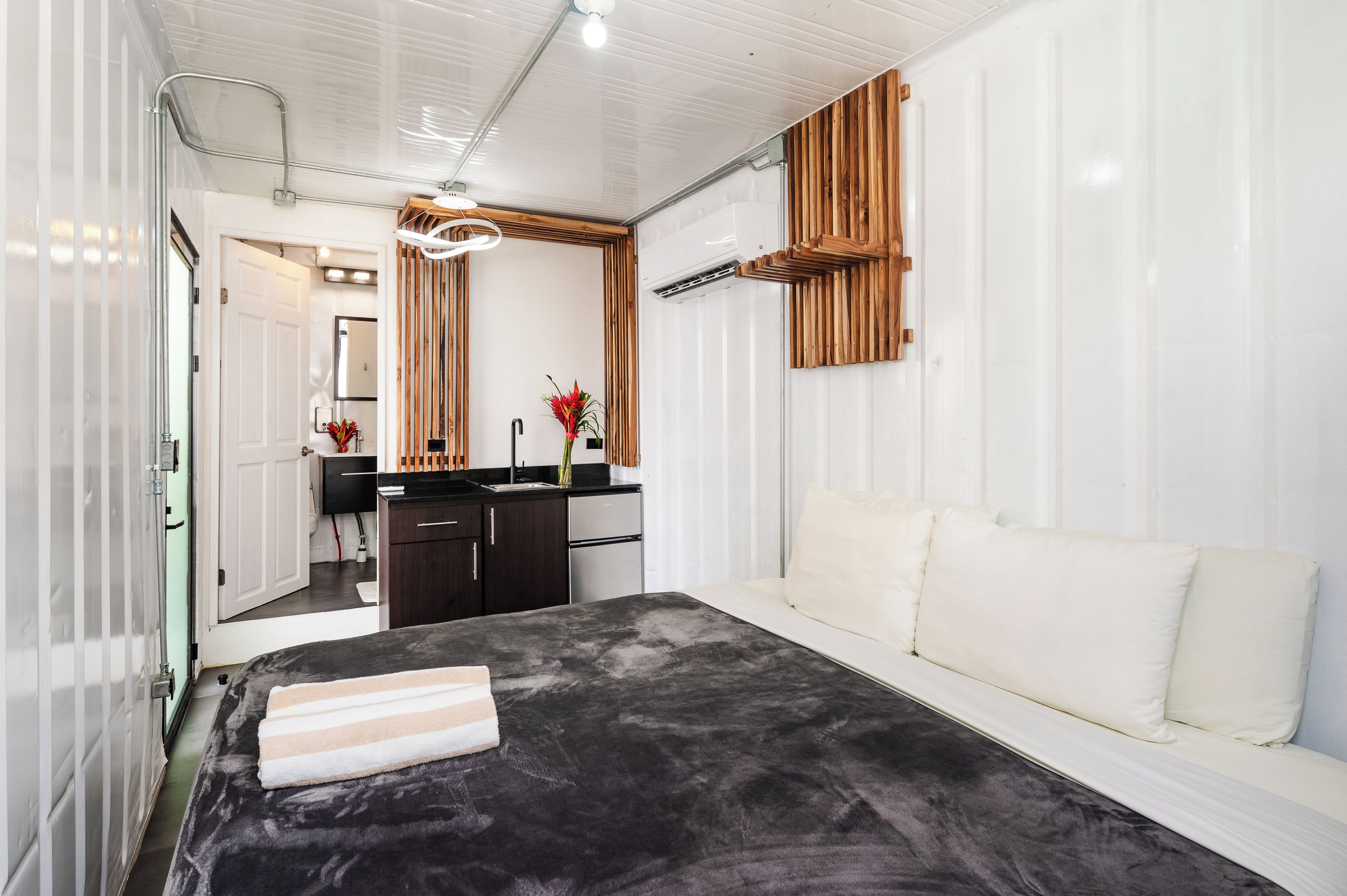 A modern bedroom with a bed, a bedside table, a mirror, a dresser, and a built-in wooden shelf.