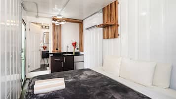 A modern bedroom with a bed, a bedside table, a mirror, a dresser, and a built-in wooden shelf.