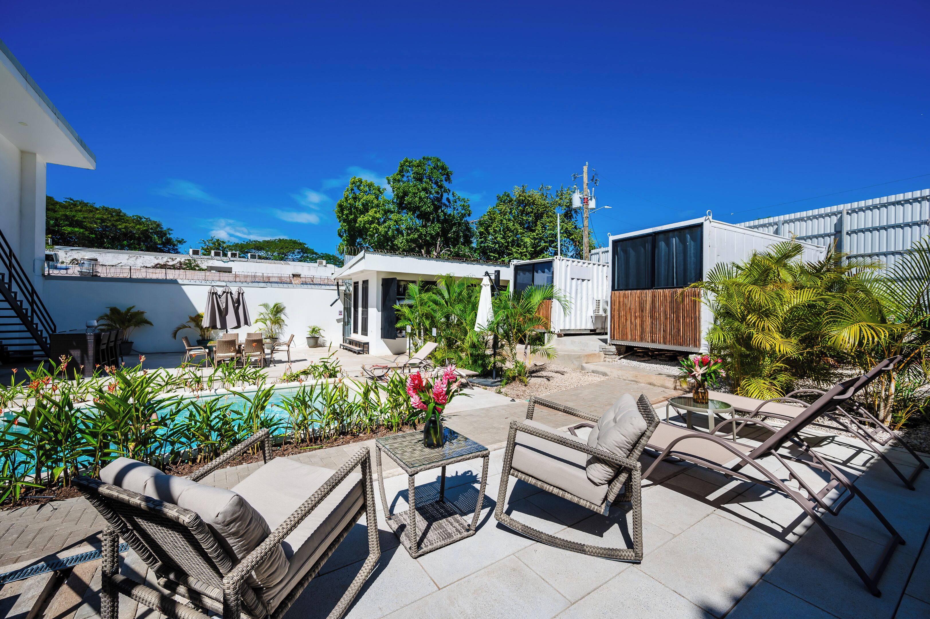 Um terraço no telhado com móveis de exterior, uma piscina e vegetação exuberante.