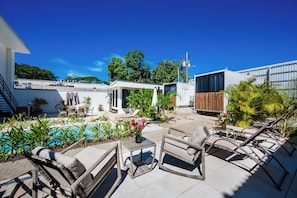 A rooftop patio with outdoor furniture, a swimming pool, and lush greenery.