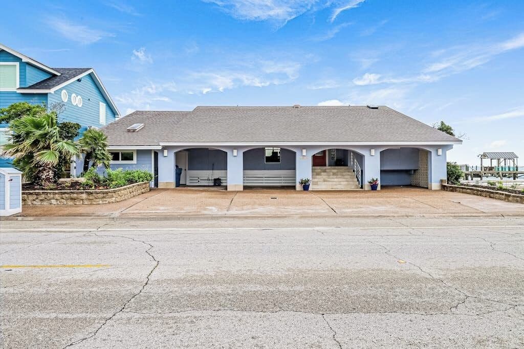 A two-story building with a flat roof, a covered front porch with columns, and a driveway leading to the entrance.
