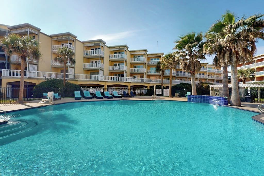 Ein Hotel mit Schwimmbad, mehreren Balkonen und Palmen.