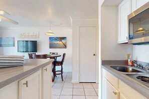 Une cuisine équipée d’un réfrigérateur, d’une cuisinière et d’un évier. On y trouve également un coin repas avec des chaises et une table.