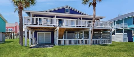 Une maison à deux étages avec un balcon, un garage et des palmiers.