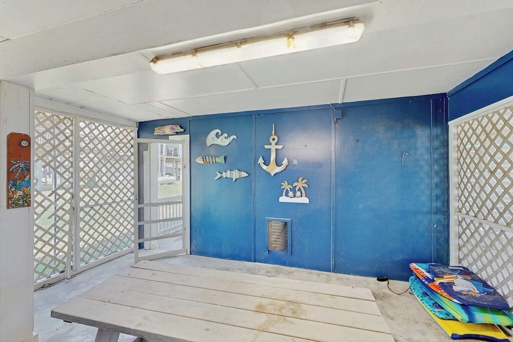 A room with a blue wall, a wooden bench, and a window with a view of the outside.